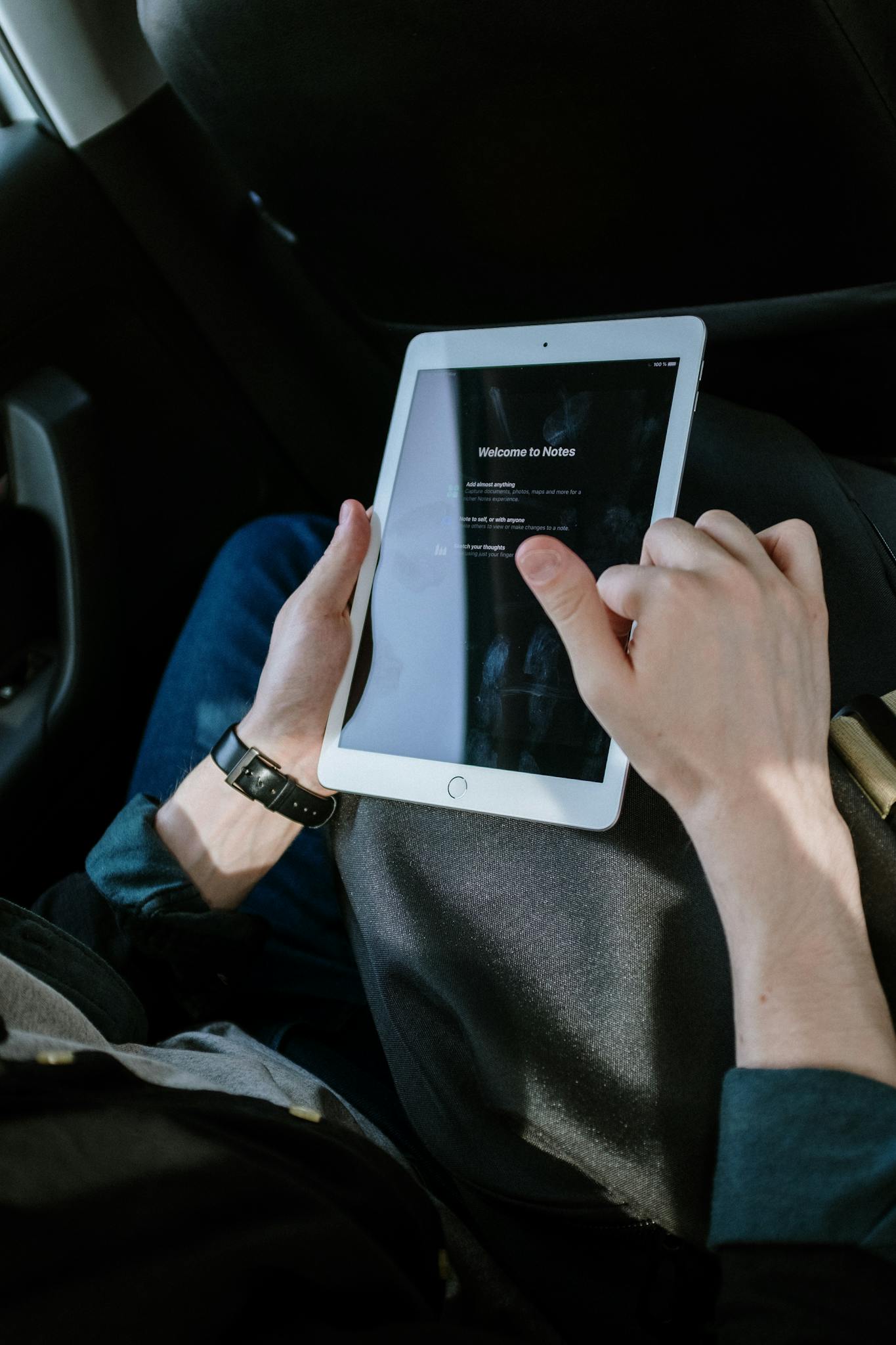 Male passenger using a tablet inside a vehicle for navigation or entertainment.